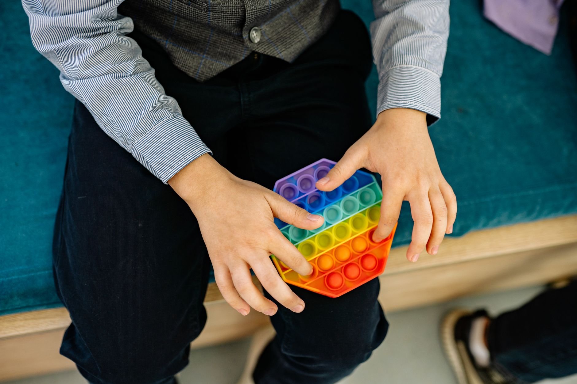 A child's hands pressing a rainbow pop it fidget toy